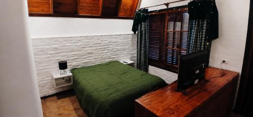 a bedroom with a green bed and a television at Monoambiente in Ezpeleta