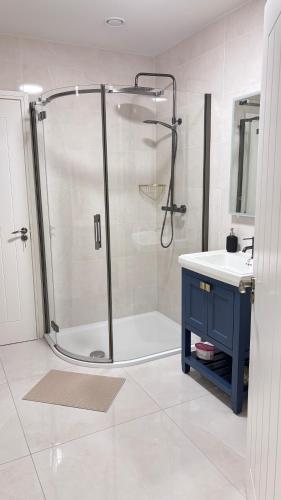 a bathroom with a shower with a blue cabinet and a sink at Patricks Thatch Cottage in Oranmore