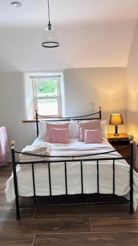 a bedroom with a bed with pink pillows and a window at Patricks Thatch Cottage in Oranmore