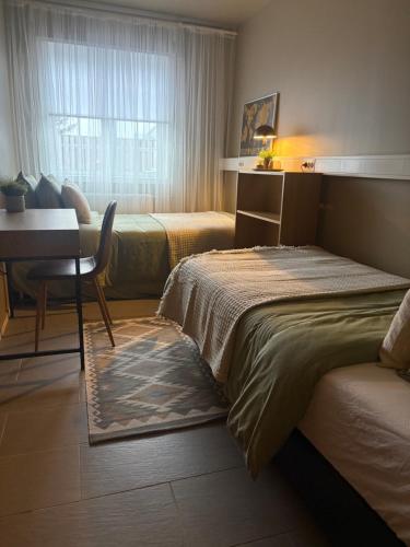 a bedroom with two beds and a desk and a window at Nupan Deluxe in Keflavík