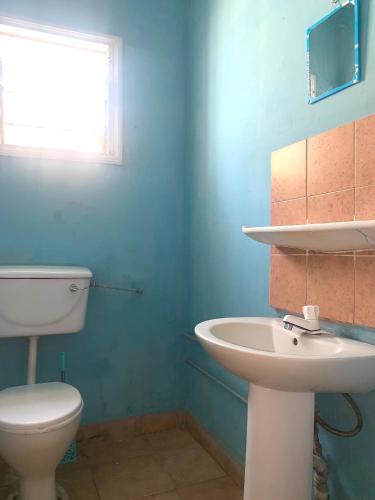 a bathroom with a white toilet and a sink at Zen villa in Old Yundum