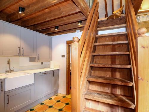 a kitchen with a wooden spiral staircase in a house at Petworth Barn in Petworth
