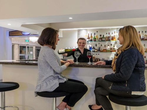 two women sitting at a bar with a glass of wine at Mercure Wagga Wagga in Wagga Wagga