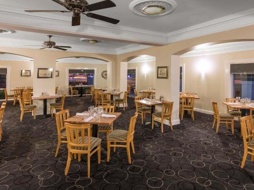 a restaurant with tables and chairs and a ceiling at Mercure Wagga Wagga in Wagga Wagga