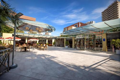 an outdoor patio with tables and chairs and umbrellas at Hotel Servigroup Pueblo Benidorm in Benidorm
