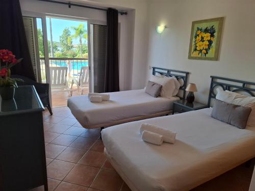 a hotel room with two beds and a balcony at Clube Alvor Ria - Waterfront luxury apartments with stunning views in Alvor