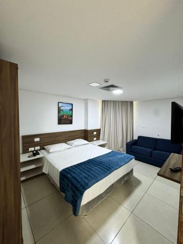 a bedroom with a large bed and a blue couch at Praiano Flat Tambaú in João Pessoa