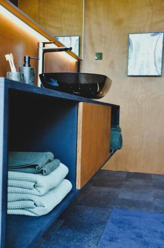 a bathroom with a sink and towels on a shelf at PARO cabin in Ignalina