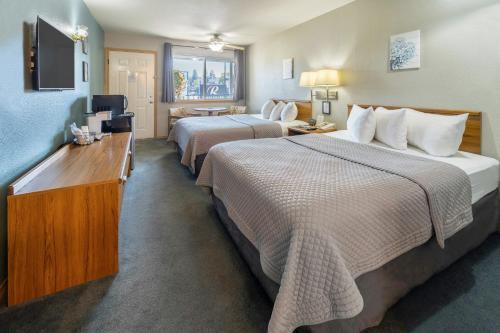 a hotel room with two beds and a television at Resort City Inn Coeur d Alene in Coeur d'Alene