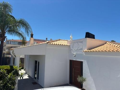 a white house with a garage and a palm tree at Villa Alvoria in Alvor