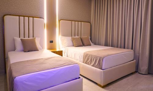 zwei Betten in einem Hotelzimmer mit weißer Bettwäsche in der Unterkunft Zumo hotel lorica in Lorica