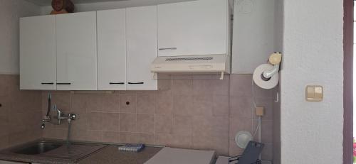 a kitchen with white cabinets and a sink at Apartman Villy 2 in Jadranovo