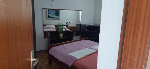 a small bedroom with a bed and a mirror at Apartman Villy 2 in Jadranovo