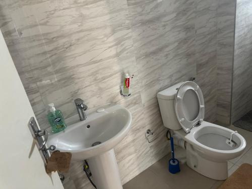 a white bathroom with a toilet and a sink at Flora House in Maputo