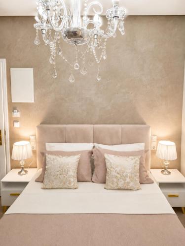 a bedroom with a large white bed with a chandelier at Studios Chrissi-Renovated 2026, Just 20m from the Beach in Skala Sotiros