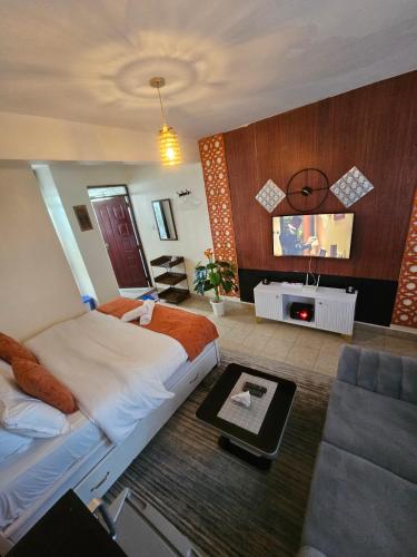 a bedroom with a large bed and a flat screen tv at Pinnacle Homes 254 - Kamakis in Ruiru