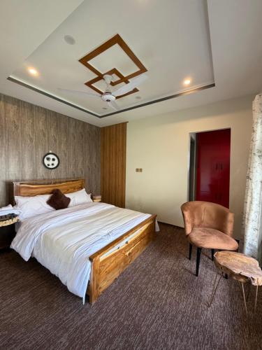 a bedroom with a large bed and a chair at Mariner Lodge Skardu in Skardu