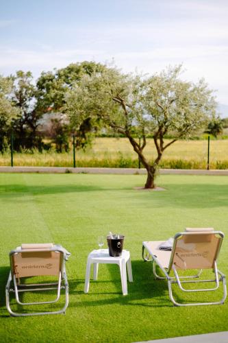 two chairs and a table in a field with a tree at Aura Otto Luxury Living in Alexandroupoli