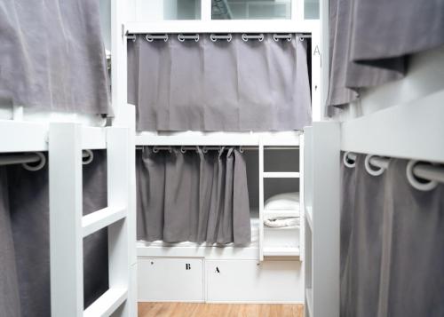 a white bunk bed with black curtains in a room at Airhostel Barcelona Airport 24h in El Prat de Llobregat