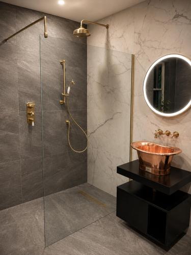 a bathroom with a sink and a glass shower at Lomond Castle Penthouse in Luss