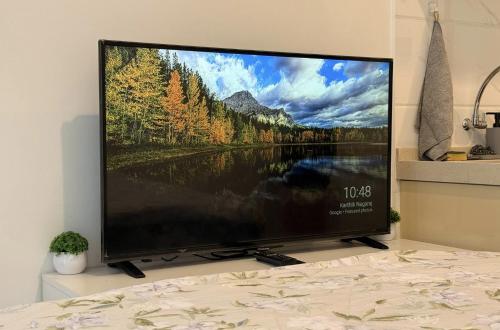 a large flat screen tv sitting on top of a bed at Calm & Comfy at Sky House BSD in Cilenggang