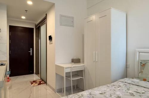 a white bedroom with a bed and a desk at Calm & Comfy at Sky House BSD in Cilenggang