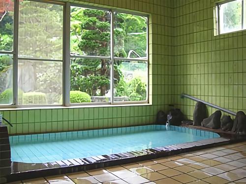 una piscina en una sala verde con ventanas en Onsen Minshuku Sakaeya, en Shizukuishi