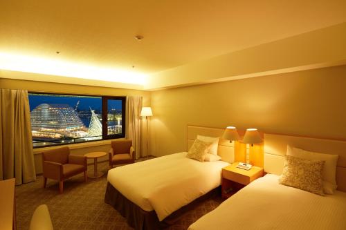 
a hotel room with two beds and a television at Hotel Okura Kobe in Kobe
