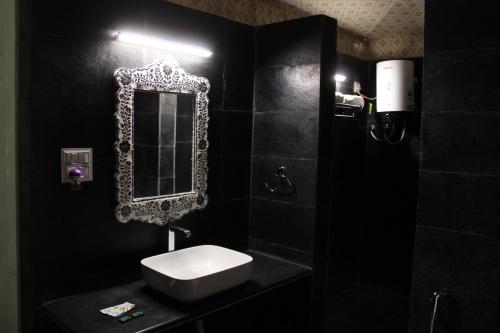 a black bathroom with a sink and a mirror at The chocolate frog in Udaipur
