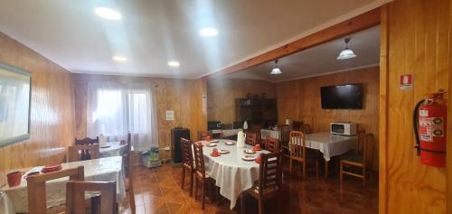 a dining room with a table and chairs and a television at Hostal Internacional Valdivia in Valdivia