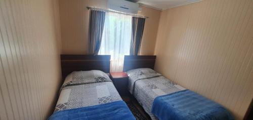 two beds in a small room with a window at Hostal Internacional Valdivia in Valdivia