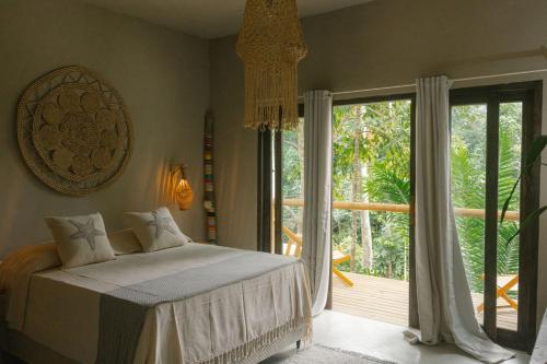 a bedroom with a bed and a large window at CASA SUKHA Hotel in Trancoso