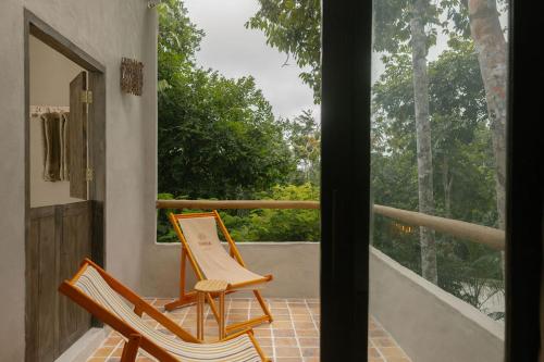 two chairs on a porch with a view of trees at CASA SUKHA Hotel in Trancoso