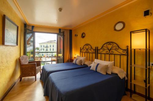 a bedroom with a bed with blue sheets and a window at Hotel A. G. Porcillan in Ribadeo