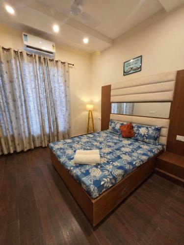 a bedroom with a bed with a blue comforter at The Cozy Theory in Kharar