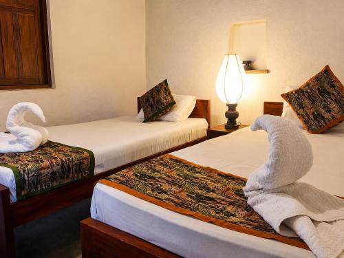 a hotel room with two beds with towels on them at Eth Mansala in Sigiriya