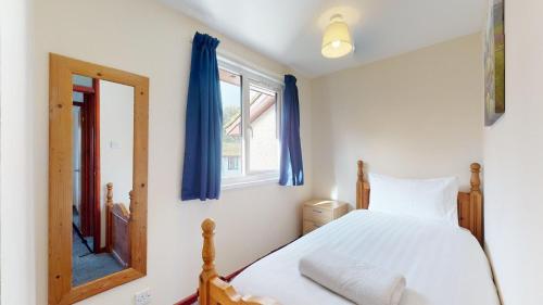 a bedroom with a bed with blue curtains and a mirror at 39 Strawberry Hill, Tolroy Manor in Hayle