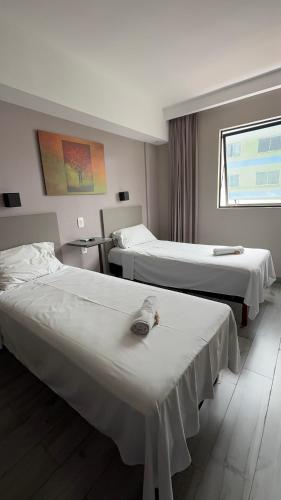 a hotel room with two beds and a window at Íbis Styles Itaúna in Itaúna