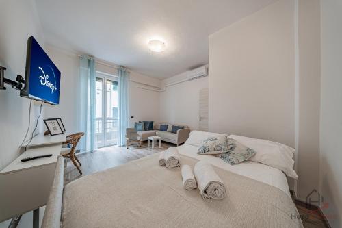 a bedroom with a bed and a desk with a television at Historic Hub - Crociere a 10 min - AC - WiFi Gratis in Savona