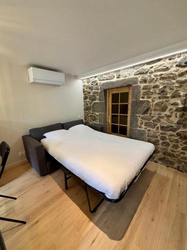 a bed in a room with a stone wall at Charmant studio en Auvergne in Orcines