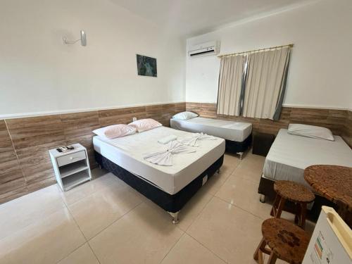 a room with two beds and a table and chairs at Pousada Sol Nascente in Piranhas