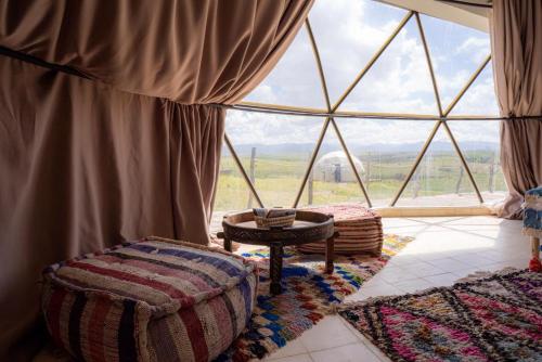 a room with a large window with rugs and a table at Agafay Valley in Marrakesh