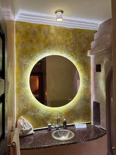 a bathroom with a sink and a large mirror at Riad Al Ibtikar in Marrakesh