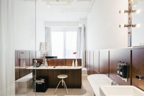 un bagno con un lavandino e un bancone con uno sgabello di Ruby Lilly Hotel Munich by IHG a Monaco