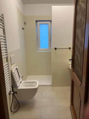 a bathroom with a toilet and a window at Casa Nina in Valbravenna