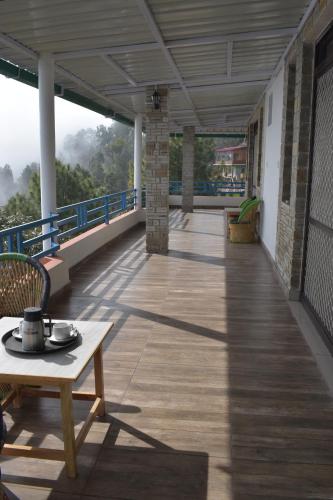 a balcony of a building with a table and chairs at Rudraa Himalayan Retreat in Hawālbāgh