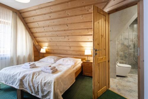 a bedroom with a bed and a bathroom with a tub at Góralski Gościniec & SPA in Poronin