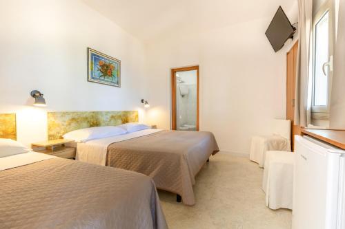 a hotel room with two beds and a mirror at San Carlo - Terrazzo sul Mare con Ristorante e Pizzeria in Zambrone