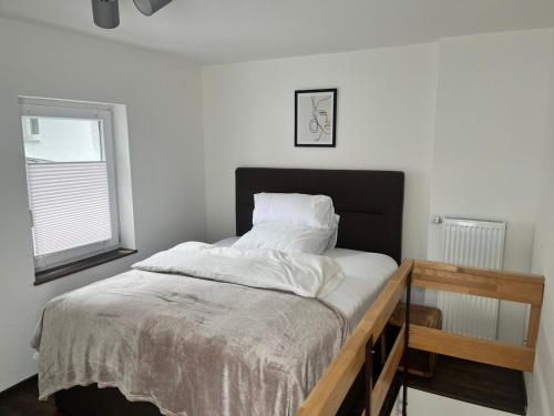 a bedroom with a bed with white sheets and a window at Amara in Siegburg