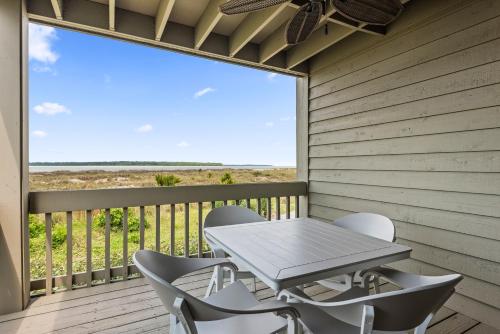 a table and chairs on a deck with a large window at 1325 Pelican Watch Villa in Seabrook Island